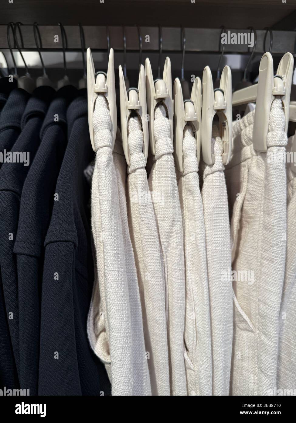 White fabric rolls stacked in a textile store display, showcasing material texture and color contrast. Mobile photo Stock Photo