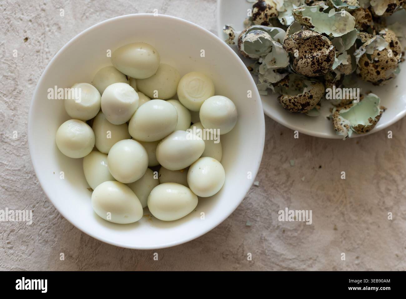 Boiled Quail Eggs in white bowl on table. Stock Photo