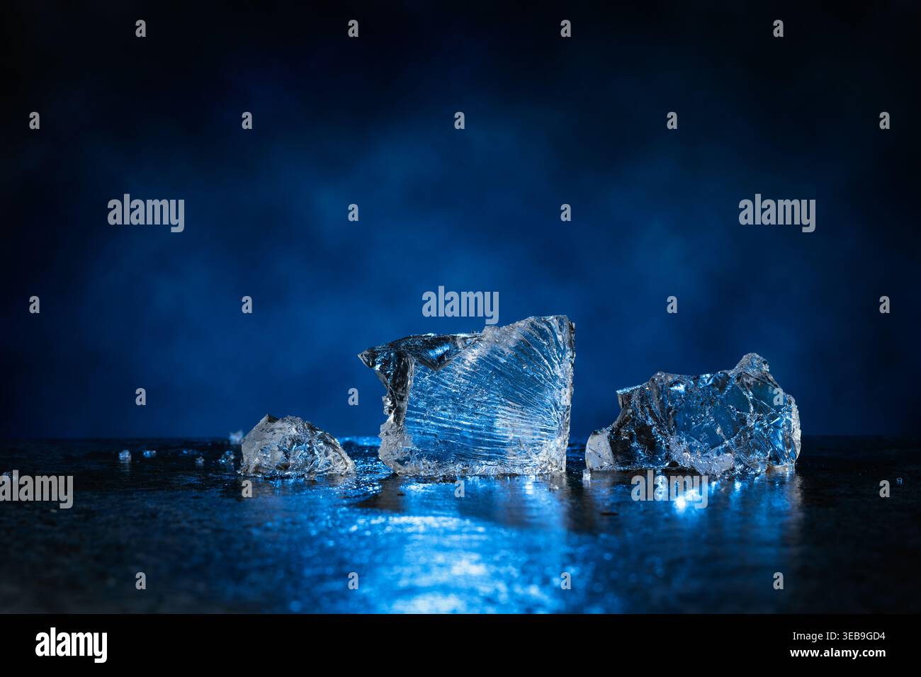 Broken ice with blue backlight on a dark background. Copy space. Stock Photo