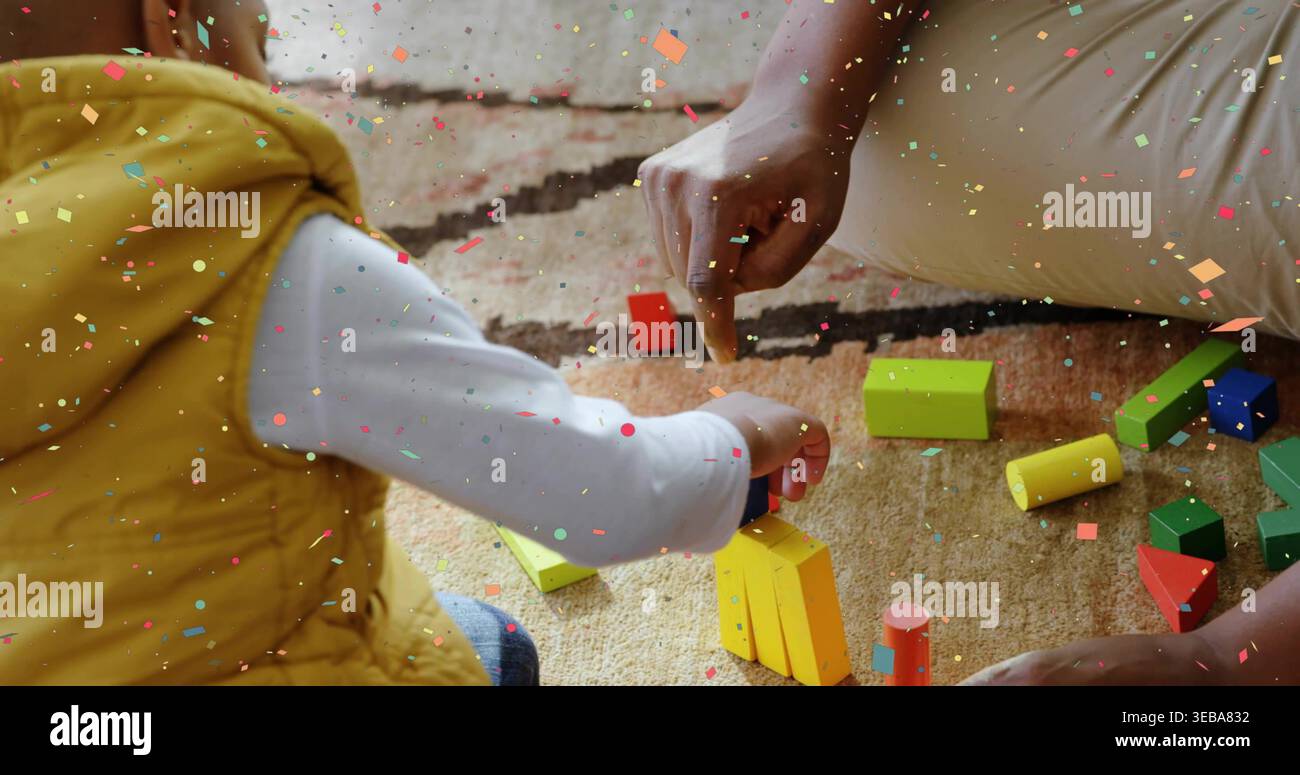 Stacking blocks child in yellow vest reaching toward yellow stack on rug, confetti overlay Stock Photo
