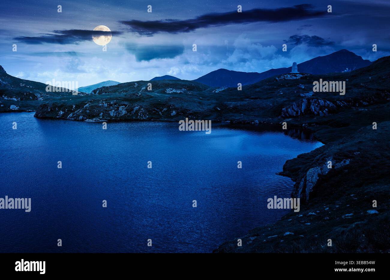 mysterious summer scenery of alpine capra lake with steep slopes at night. fantasy view of transylvania alps, sibiu county. full moon over southern ca Stock Photo