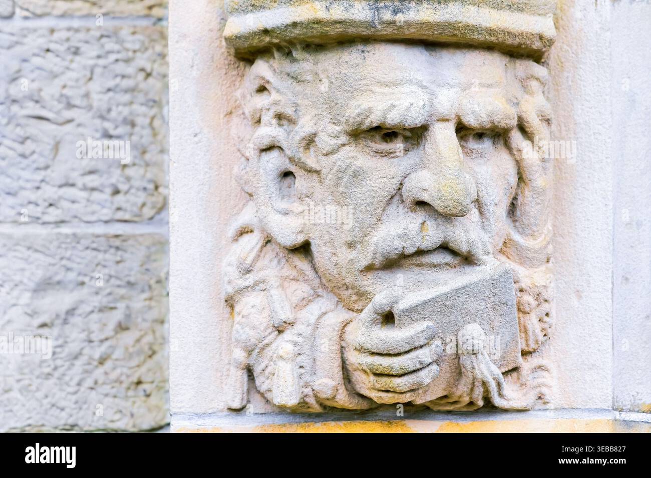 Stone carved figure holding book relief. Architectural feature of the ...