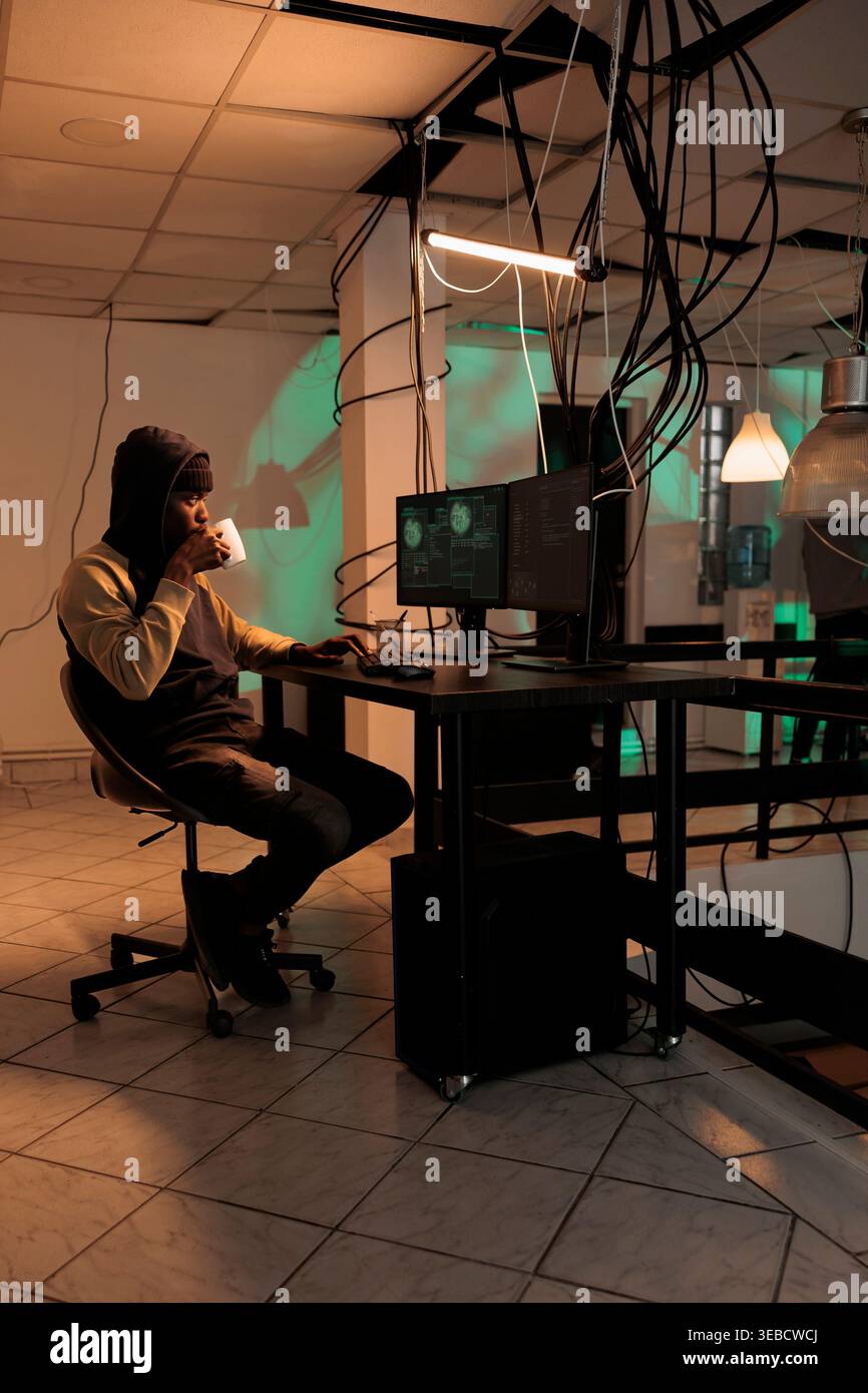 Young man working on security breach hacking, committing cyberterrorism and stealing personal data. causing computer malware at night. Online criminal cracking server encryption. Stock Photo