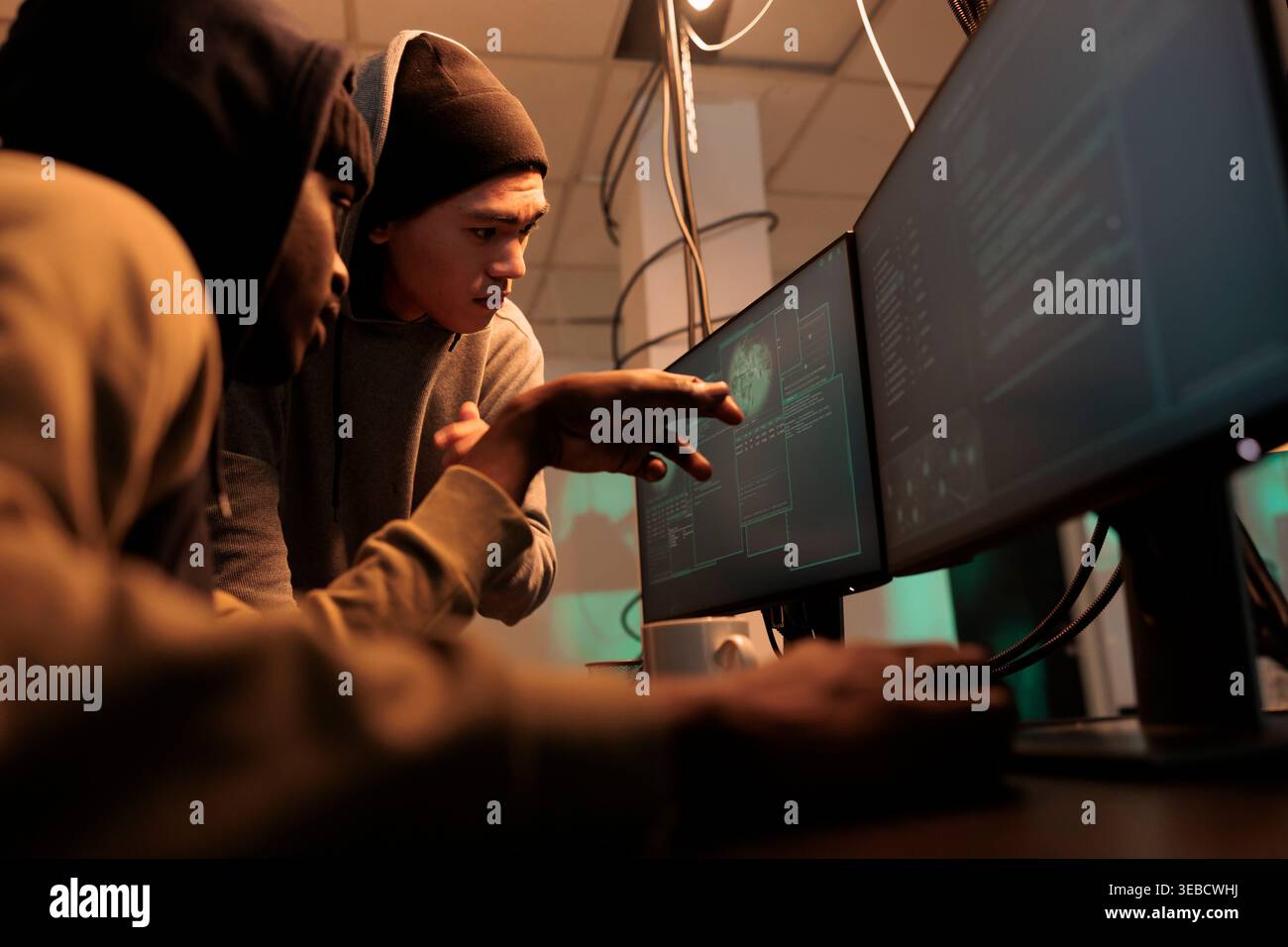 Hackers discussing computer system password cracking, coding malware, cybercrime. Criminals developing internet virus, scammers programming malicious software at night time Stock Photo