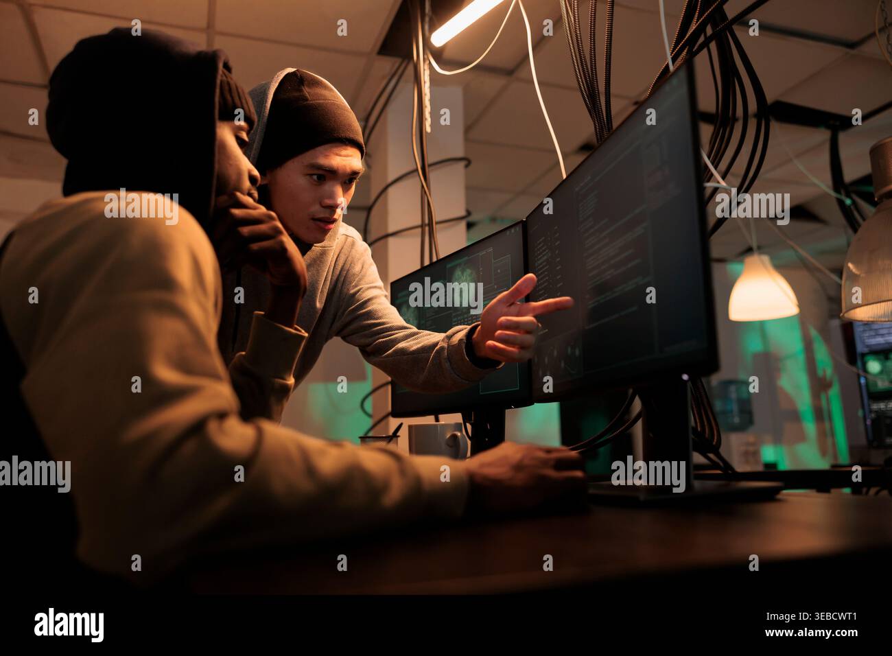 Hackers discussing computer system hacking, coding malicious software, cybercrime. Criminals planning cyberattack, programming internet virus, stealing data at night time Stock Photo