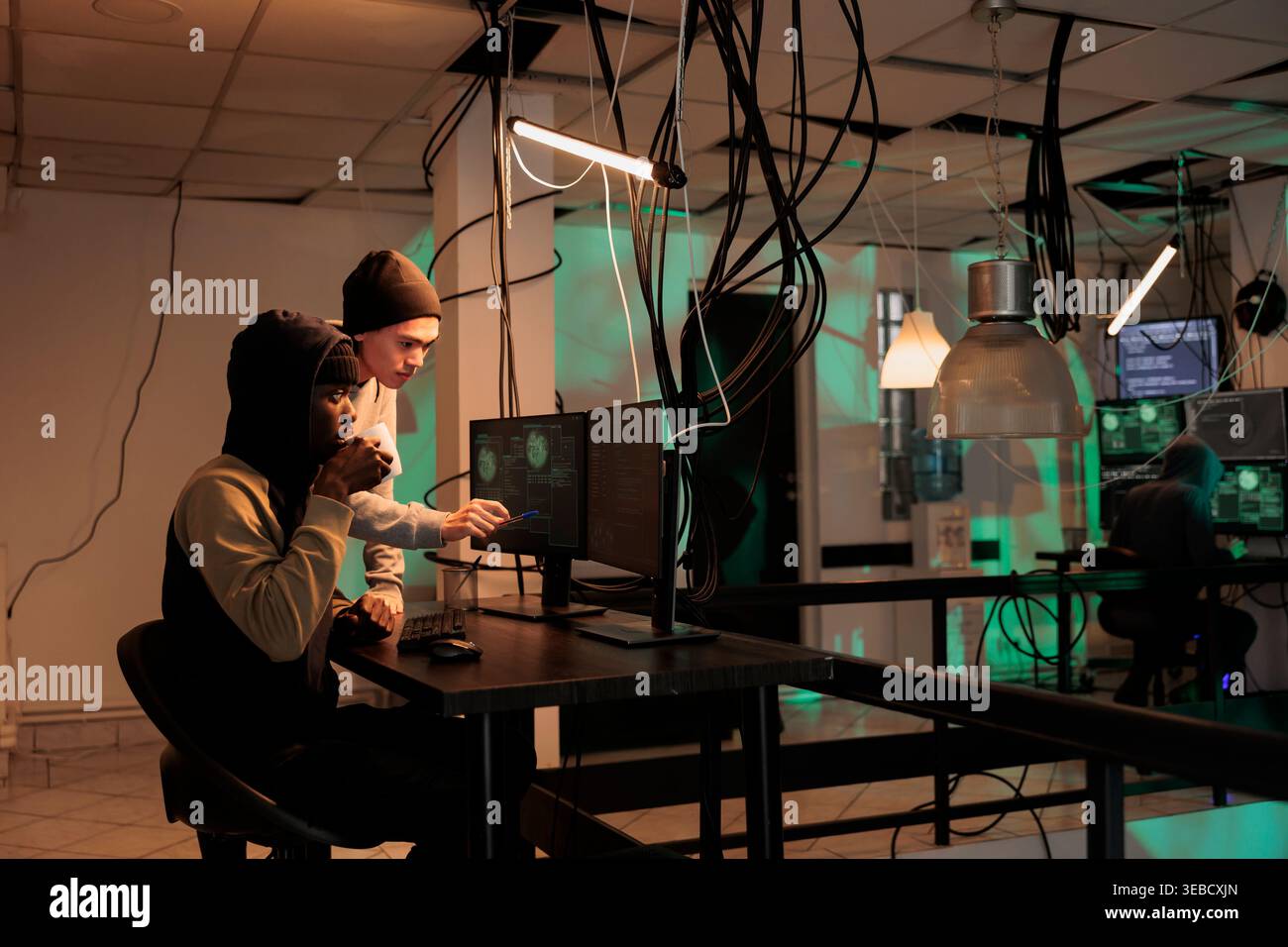 Hackers group coding internet virus program, developing malicious software, criminals stealing privacy information. Cybercrime, scammers hacking computer system, breaking into database at night time Stock Photo