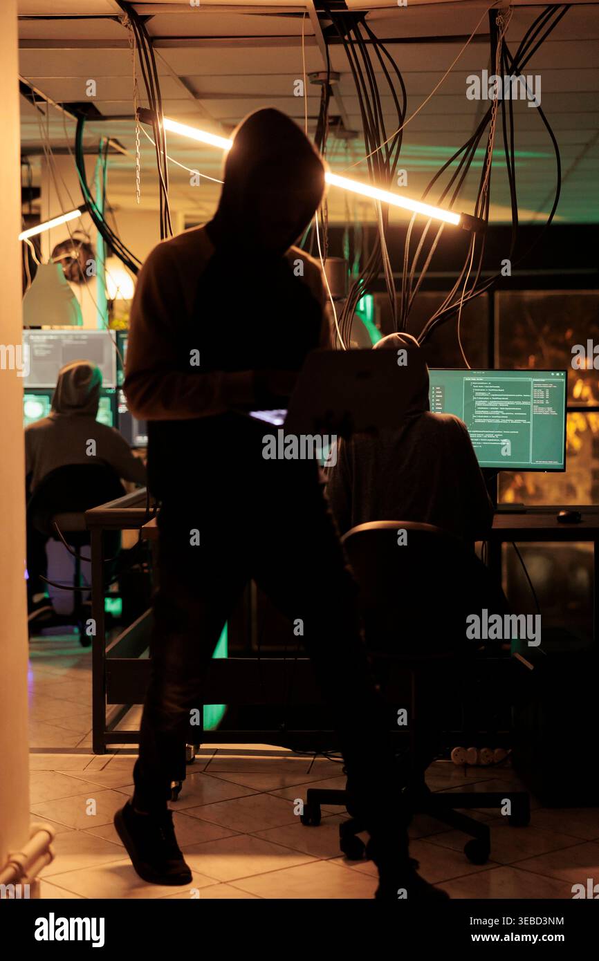 Cyber criminals team hacking computer system, coding malicious software, cracking database password, stealing information, data breach. Cyberterrorism, internet thieves in hoods hacking server Stock Photo