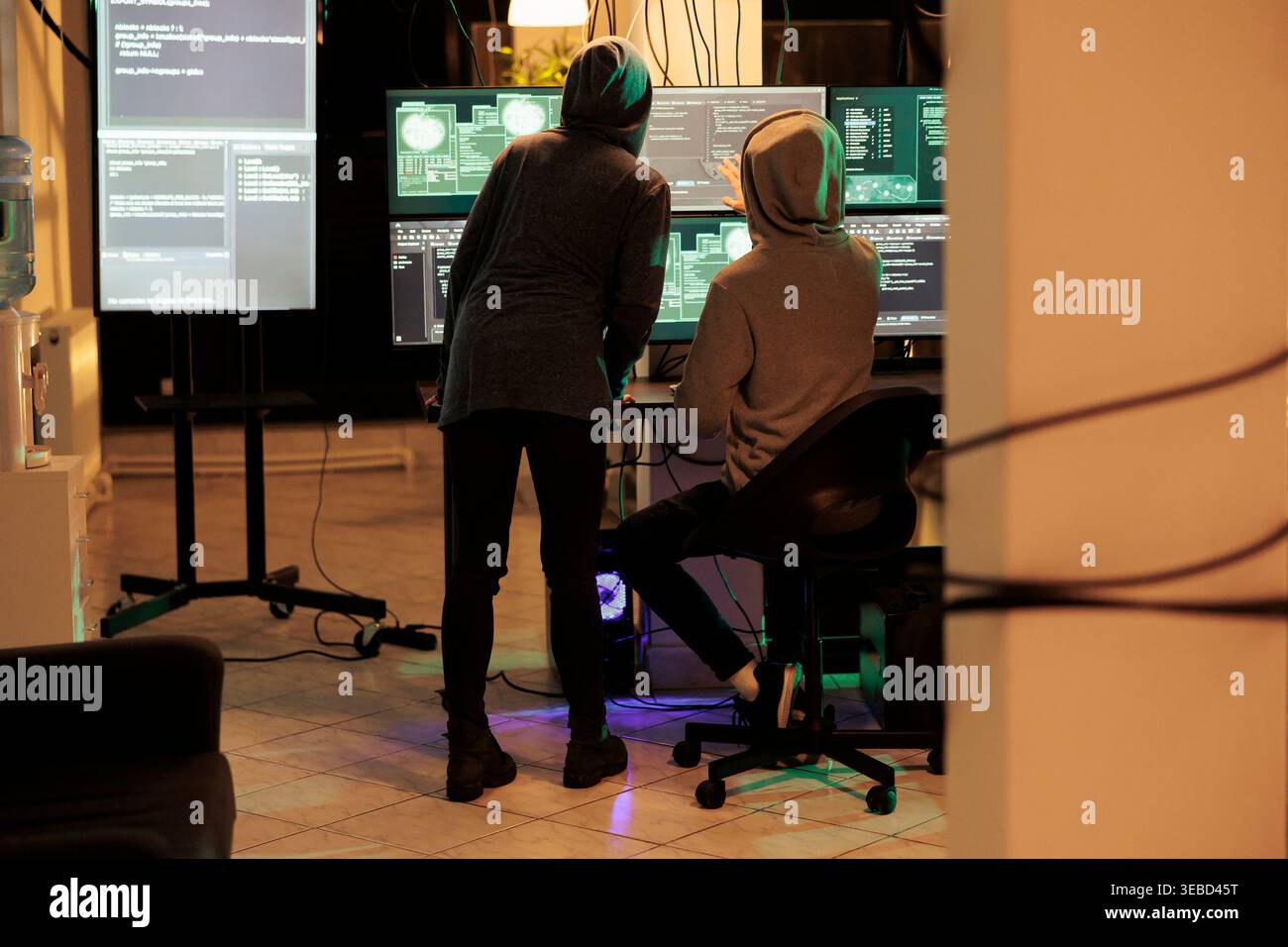 Team of cybercriminals cracking server encryption and hacking system, working on cyberterrorism at night. Young hackers doing criminal activity, stealing sensitive information. Stock Photo