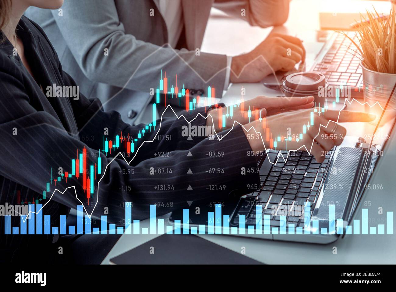 Two business professionals analyze financial data with digital graphs and charts on laptops in a modern office, highlighting teamwork and decision Stock Photo
