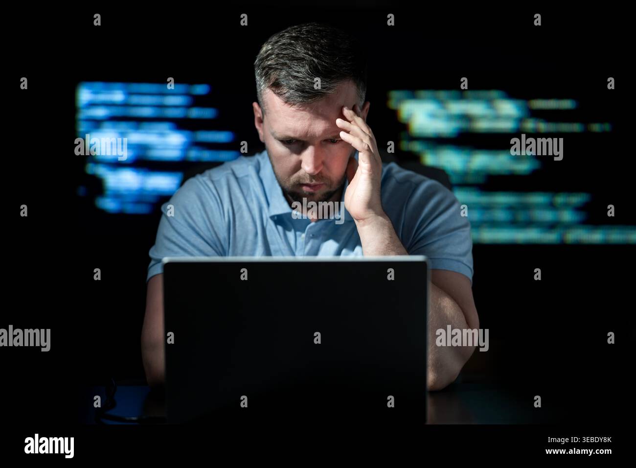 Cybersecurity hacker works on laptop. Cybersecurity hacker analyzes green code. Cybersecurity hacker monitors network threat. Cybersecurity hacker Stock Photo