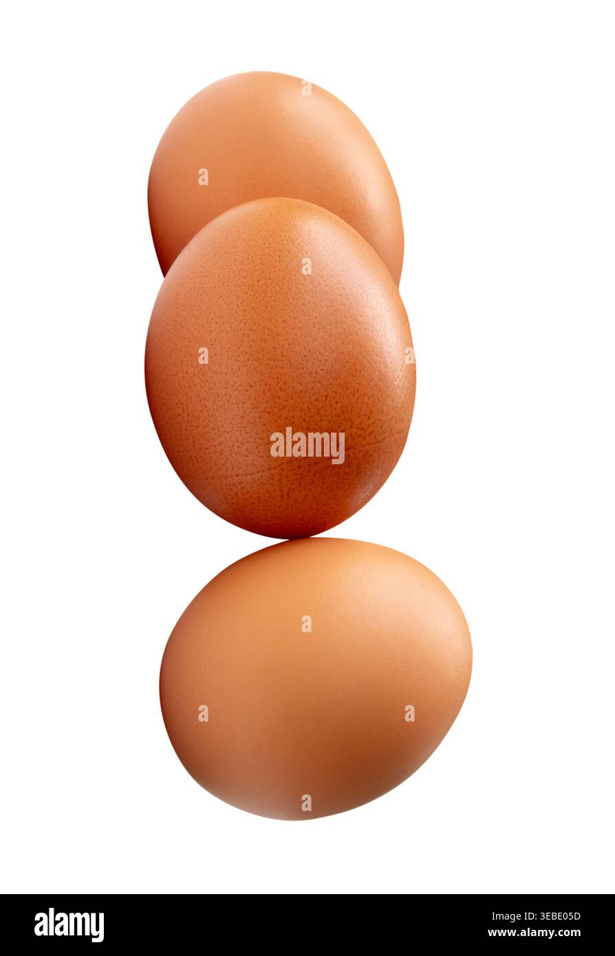 Three raw brown chicken eggs in stack are isolated on white background with clipping path. Stock Photo