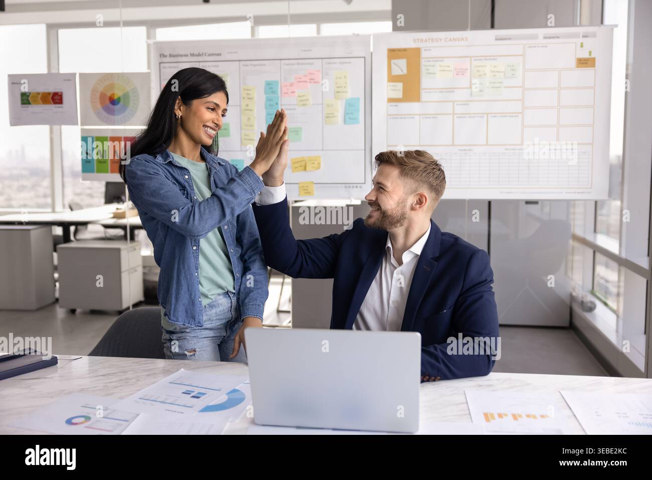 Two happy multinational colleagues exchanging high five Stock Photo
