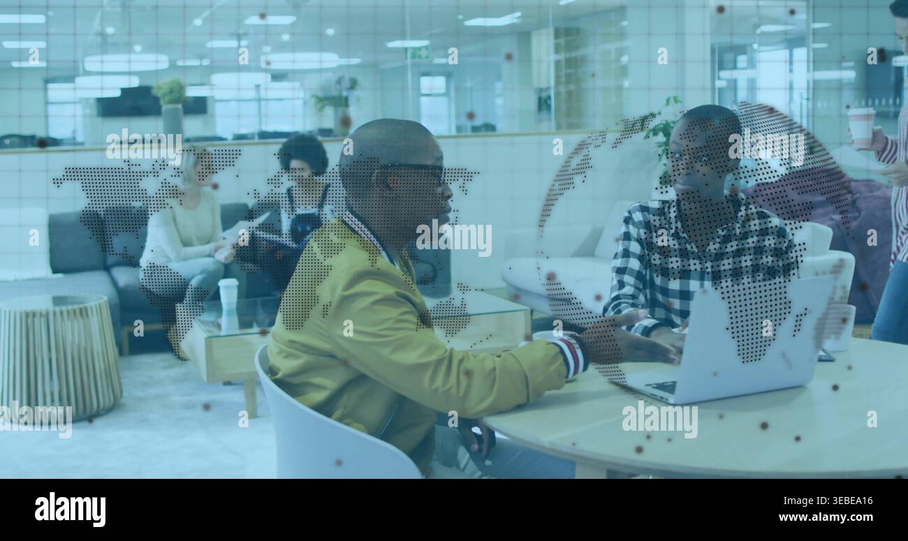 Talking two men, mustard-jacket, using laptop on round-table at office lounge with dotted map panel Stock Photo
