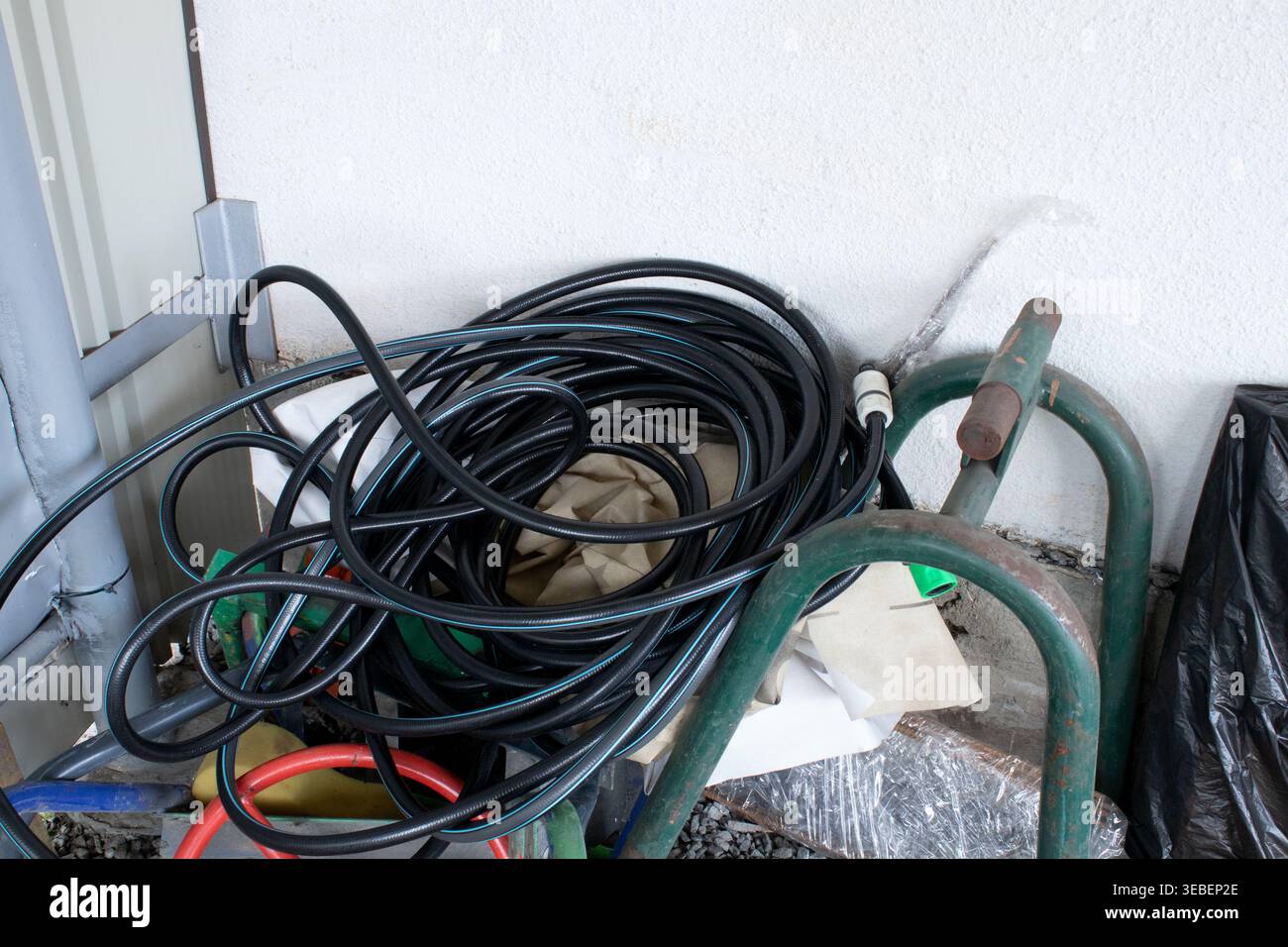 Water hose for irrigation is rolled into a ring. New long hose on concrete background top view Stock Photo