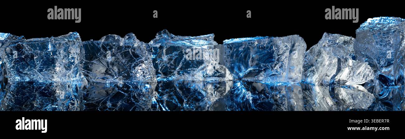 Broken ice with blue backlight on a black reflective background. Copy space. Stock Photo