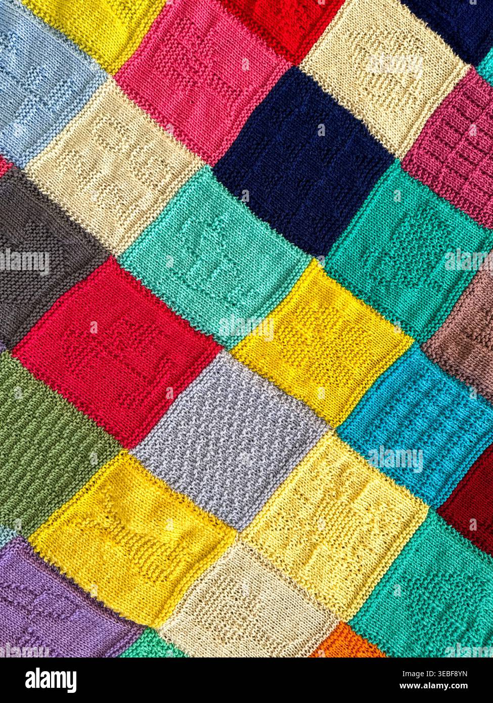 Pattern of squares on a knitted blanket using different coloured wool. Backgrounds. Stock Photo
