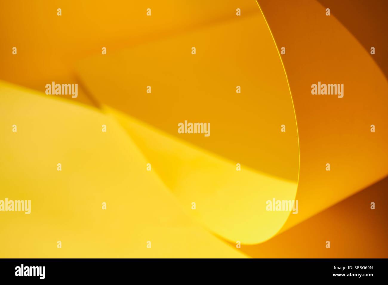 Yellow paper surface creating abstract curves, light and shadows Stock Photo