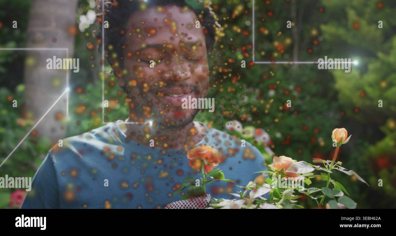 Smiling man wearing blue tee and glove smelling potted peach rose plant in backyard, AR overlay. Garden, blooms, greenery, foliage, daylight, outdoor, Stock Photo