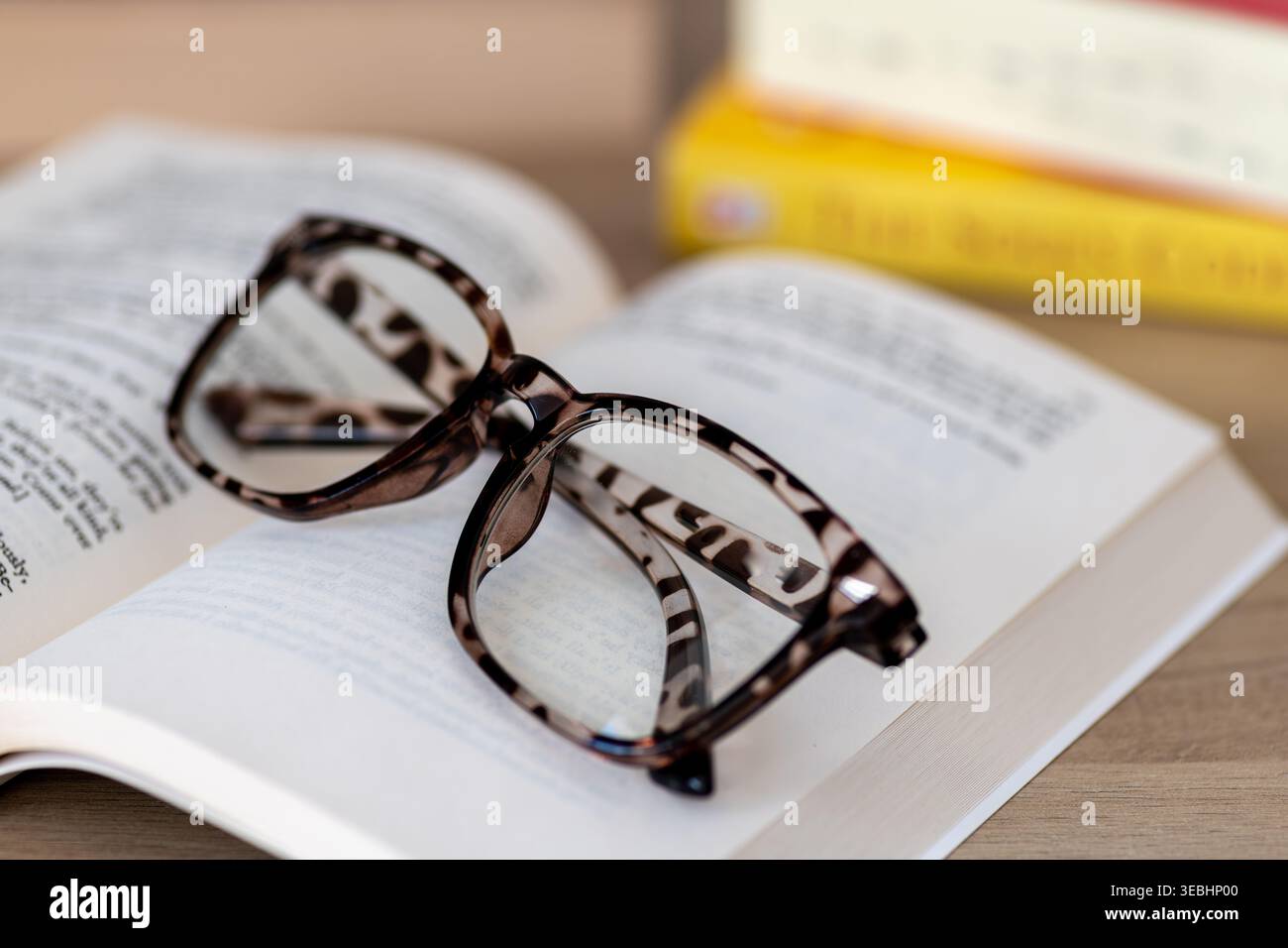 A closeup of a pair of folded reading glasses on an open book. Stock Photo