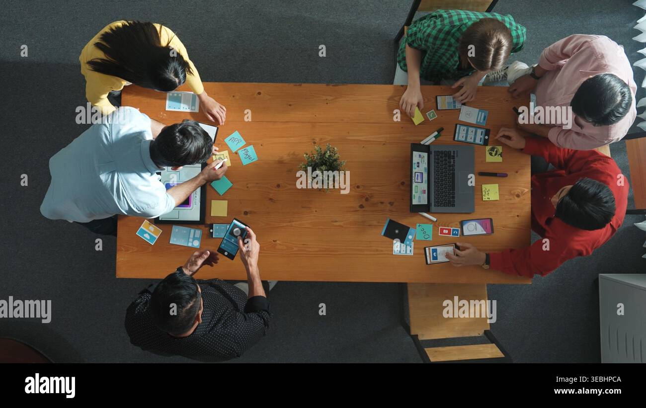 Programmer team brainstorm and plan Ux Ui design for mobile phone while present idea by using laptop at meeting. Software developer look at wireframe Stock Photo