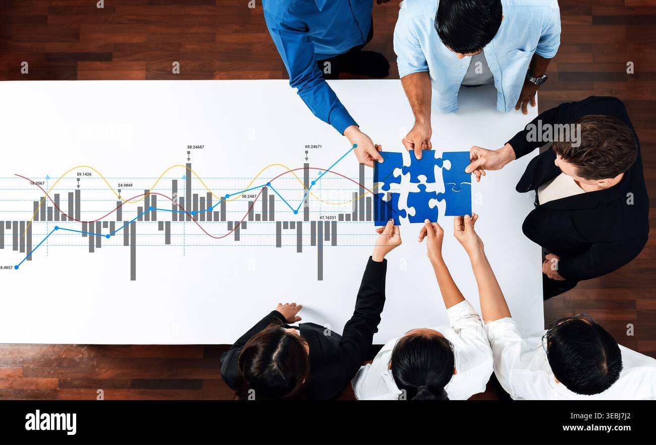 A diverse group of professionals collaborates on a business strategy. They analyze financial graphs while engaging with puzzle pieces, symbolizing Stock Photo