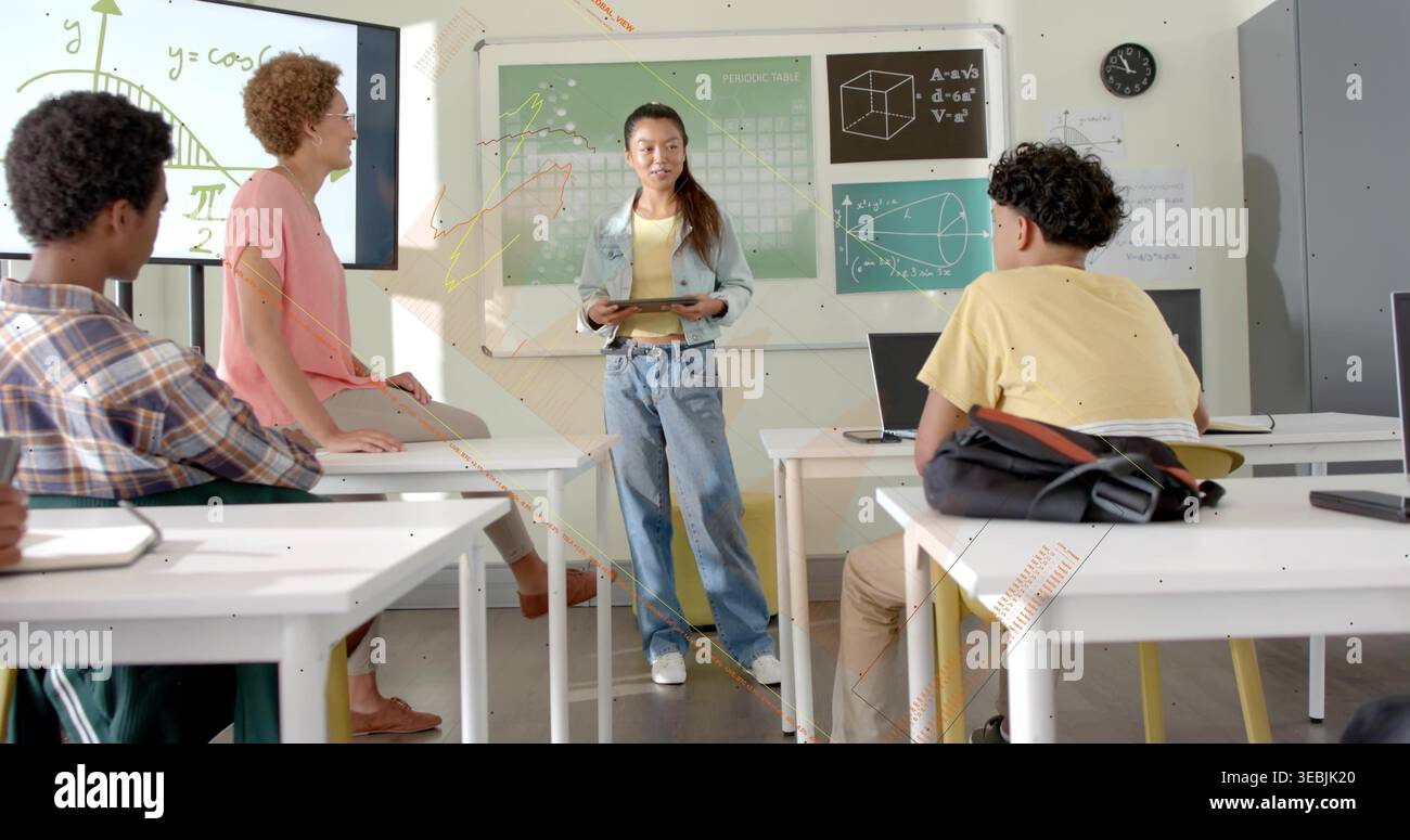 Teaching instructor holding tablet and explaining cosine graph on display in classroom with laptops Stock Photo