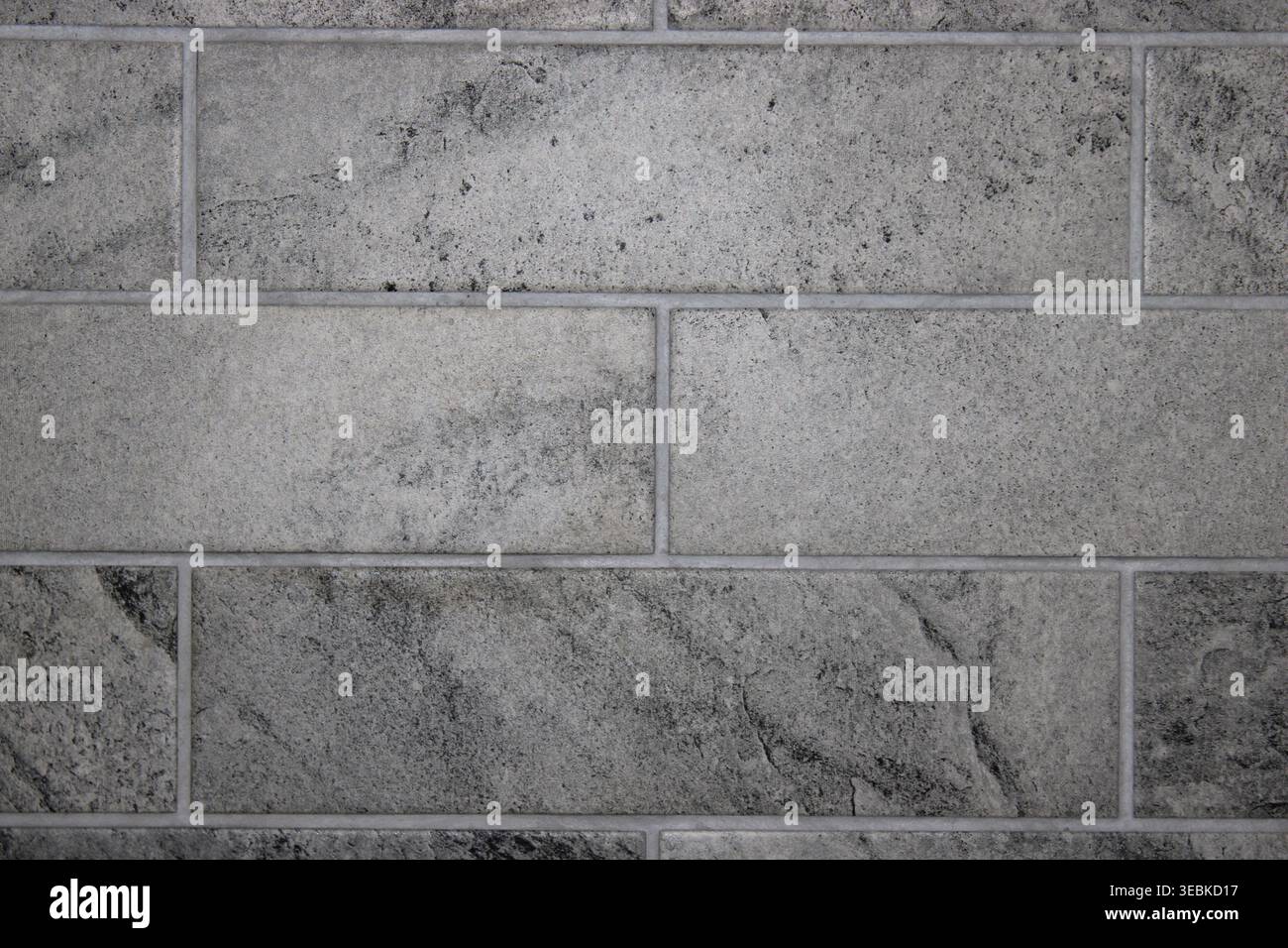 A wall covered with gray rectangular tiles forms a solid surface in a contemporary area. No decorations are present on the wall, giving it a clean loo Stock Photo