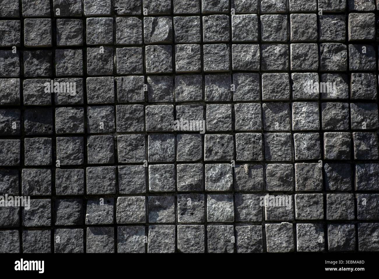 Top view of dark grey square stone pavers creating a geometric grid pattern Stock Photo