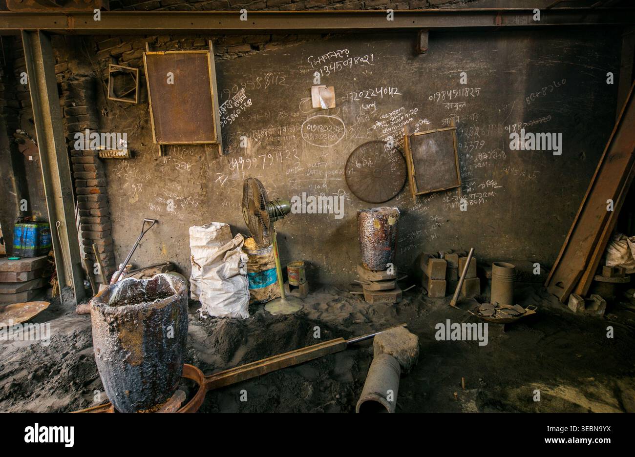 Dhaka, Bangladesh - 20 April 2026: View of a dark, grimy workshop interior, showcasing rough, textured walls with faded writings and industrial tools. Stock Photo