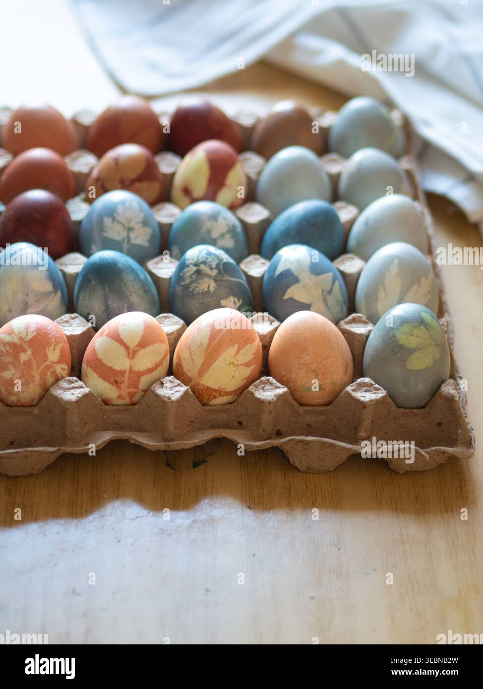 Carton with Colorful Naturally Dyed Easter Eggs on Table Stock Photo