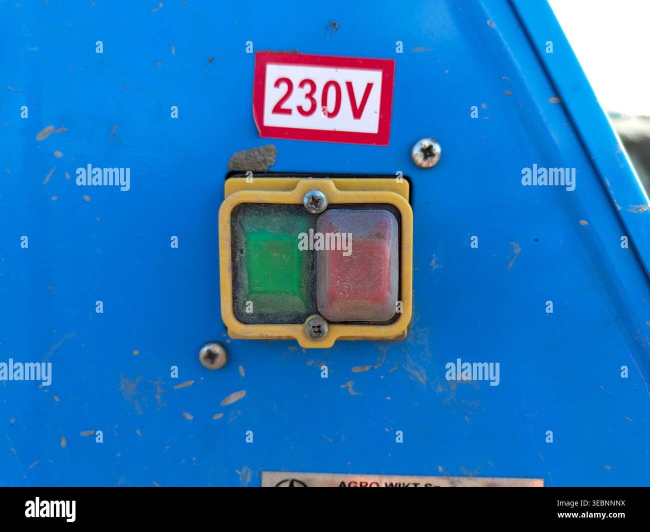 Dust Button Electrical control buttons with 230v label on blue machine panel close ...