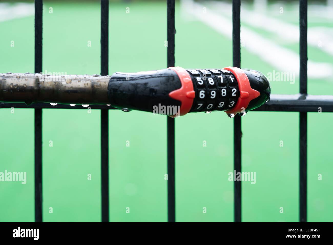 Combination lock on a rainy day securing a gate at a sports field in Berlin, Germany Stock Photo