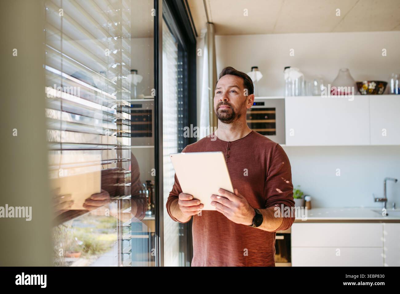 Man using smart home app to control electric window shades indoors. Stock Photo