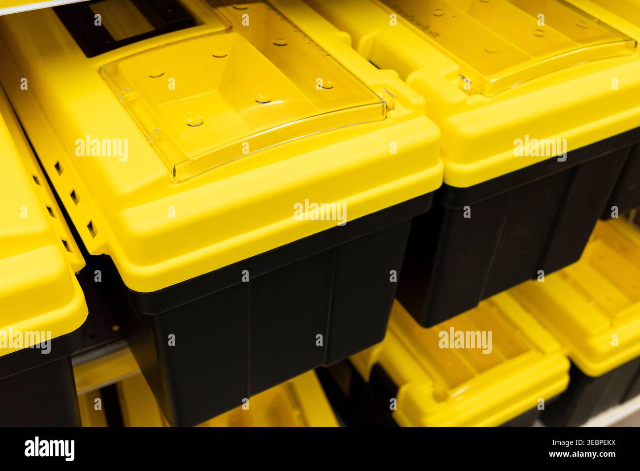 yellow plastic storage bins stacked in retail store aisle, organized container system detail. Concept: storage organization Stock Photo