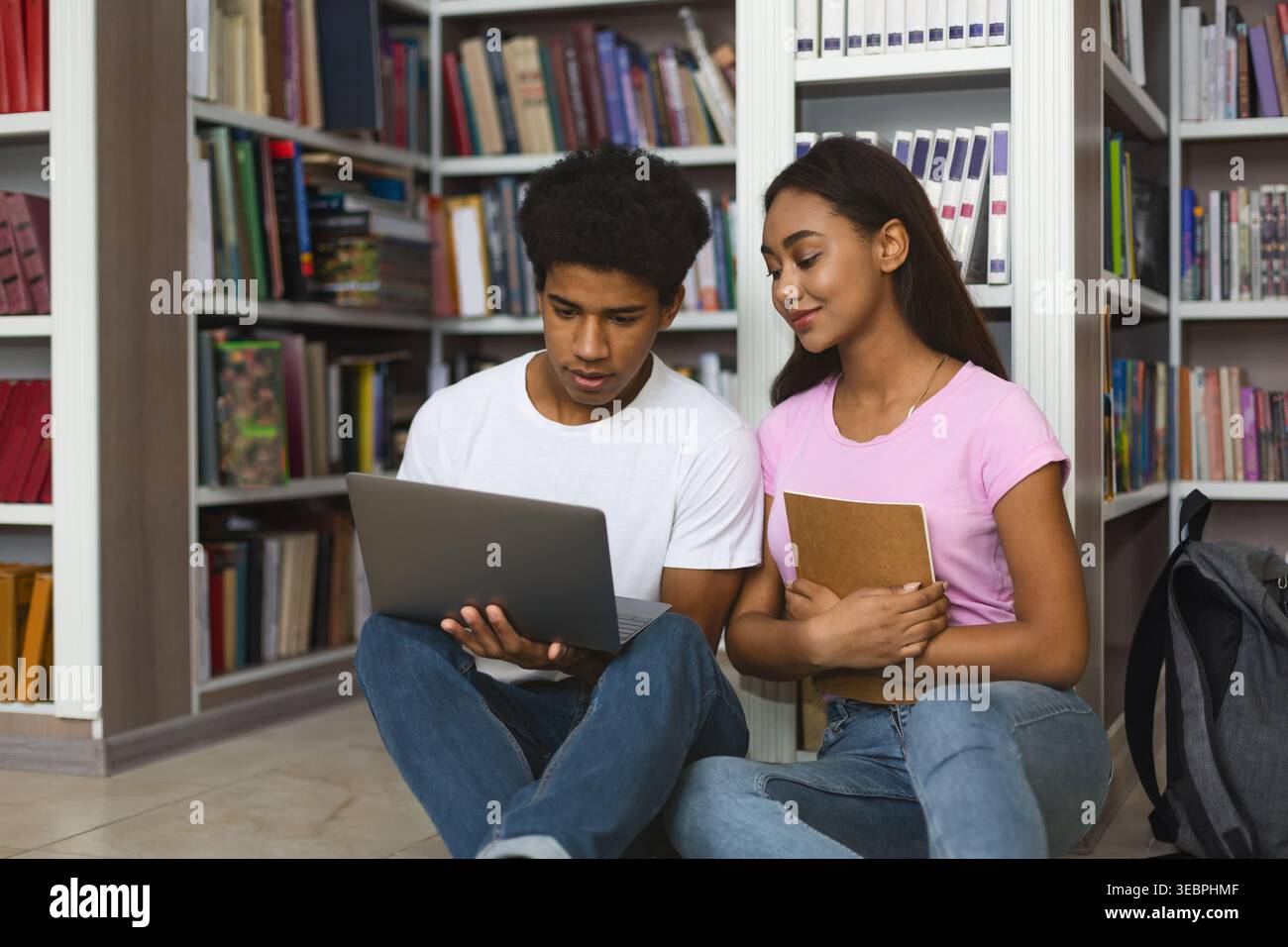 Students Collaborating on a Project While Seated on the Library Floor in a Cozy Learning Environment Stock Photo