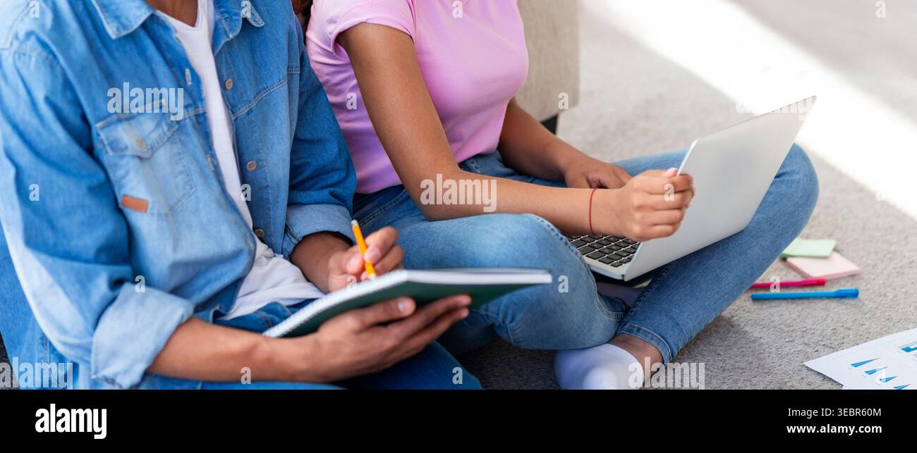 Two Students Collaborate on Homework Using a Laptop and Notebook on a Carpeted Floor Stock Photo