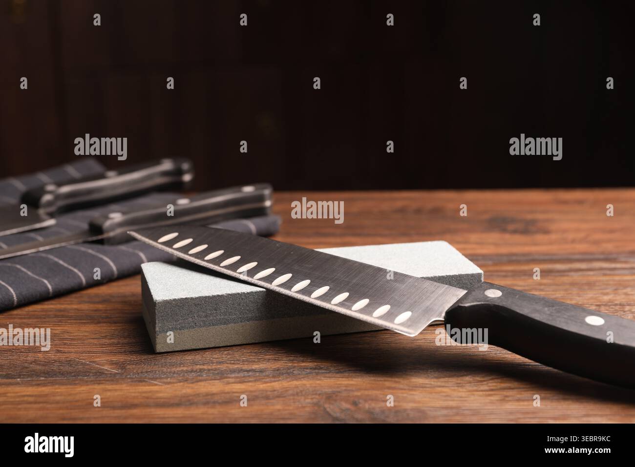 Sharpened knife and whetstone on wooden table. Space for text Stock Photo