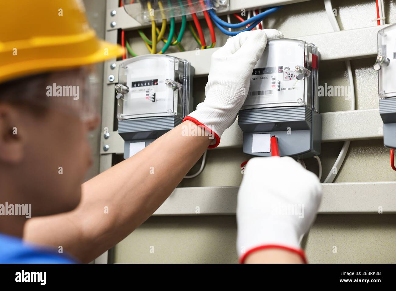 Electrician with screwdriver checking electrical meter indoors, closeup Stock Photo