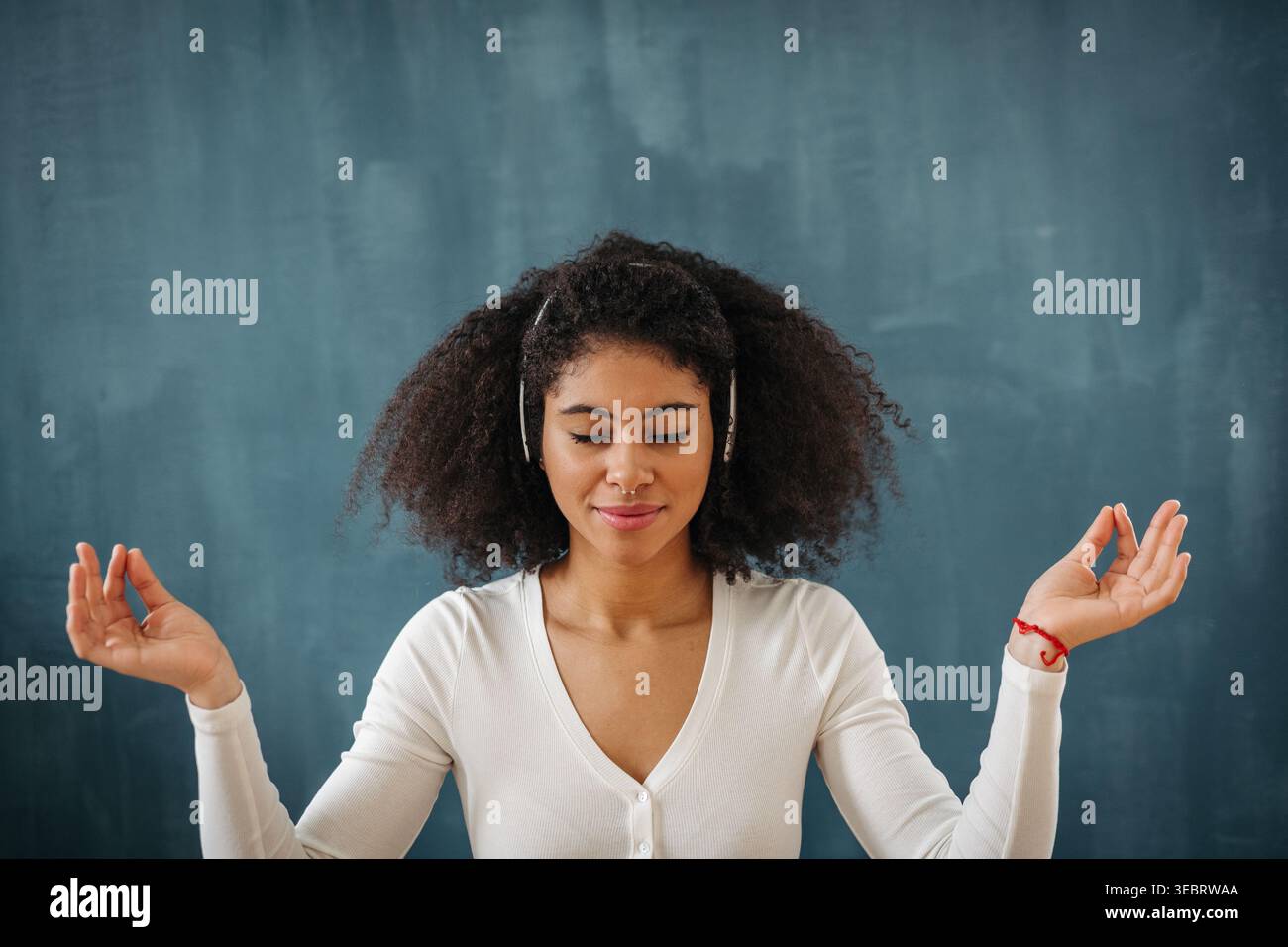 Woman listening to music and meditating with closed eyes in calm focused pose. Stock Photo