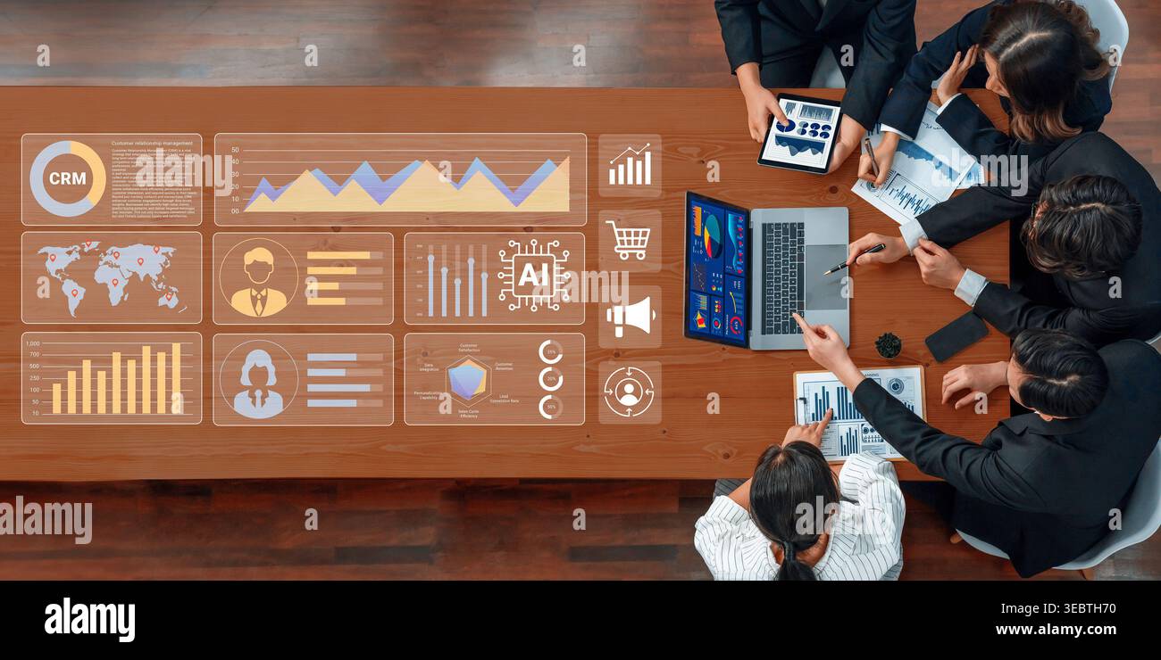 A diverse business team collaborates in a modern office setting, analyzing data and charts on laptops and digital displays, emphasizing teamwork and Stock Photo