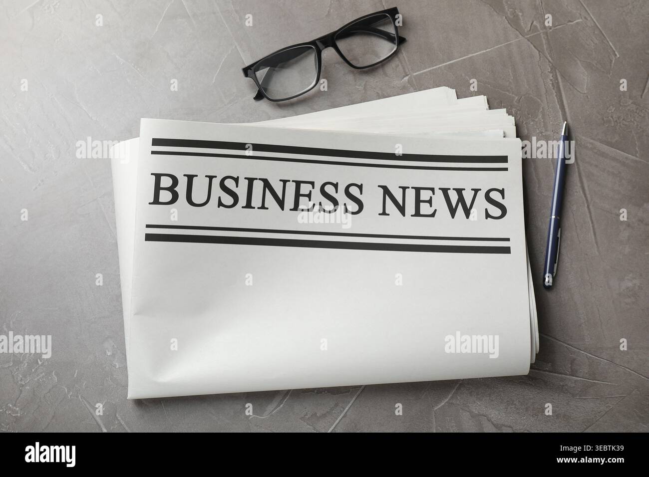 Newspaper, pen and glasses on grey table, flat lay Stock Photo