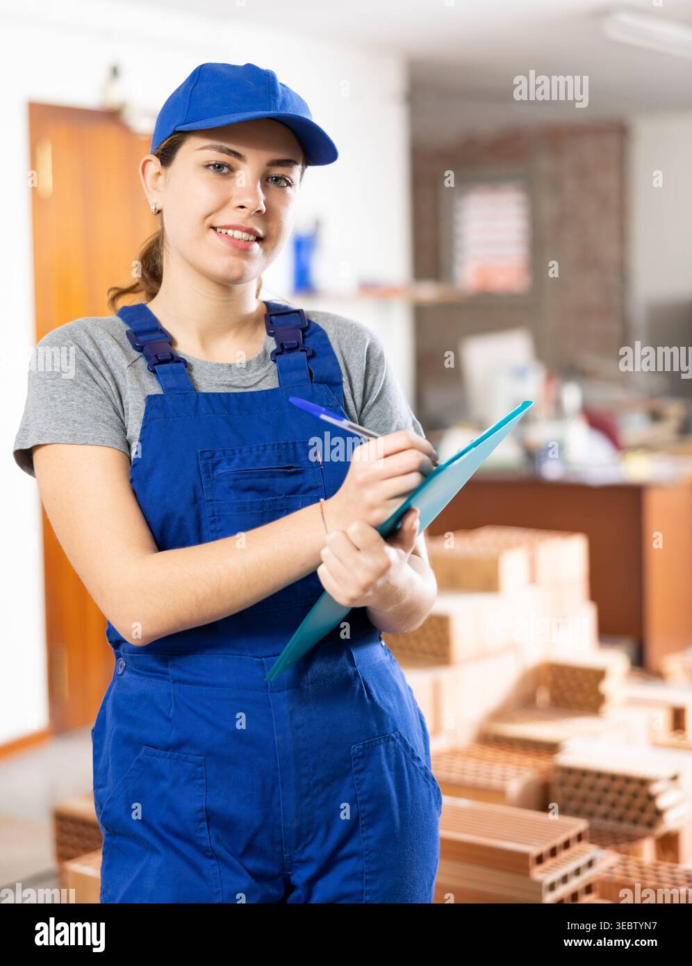 Young woman construction worker standing inside apartment Stock Photo