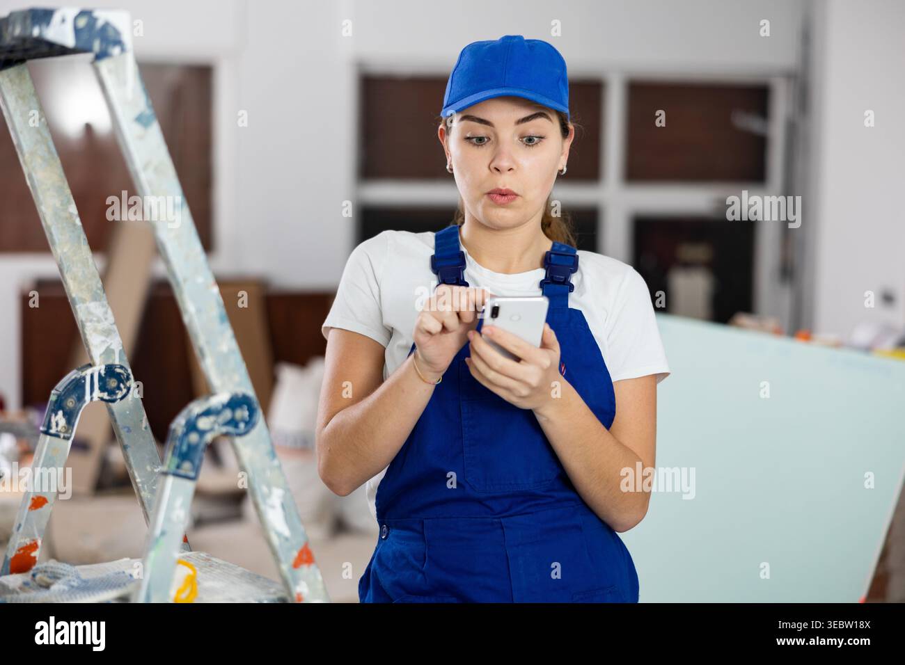 Female construction worker using smartphone in apartment Stock Photo