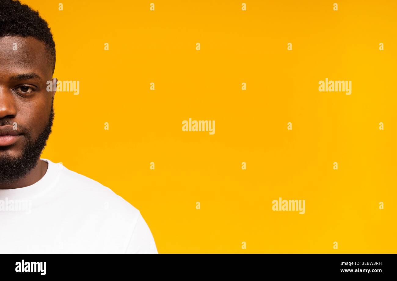 A Young Man Stands Against a Bright Yellow Backdrop, Wearing a Plain White Shirt Stock Photo