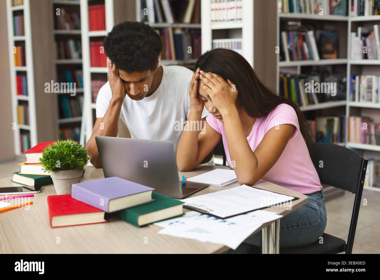 Students Experiencing Stress While Studying Together in a Library Environment Stock Photo