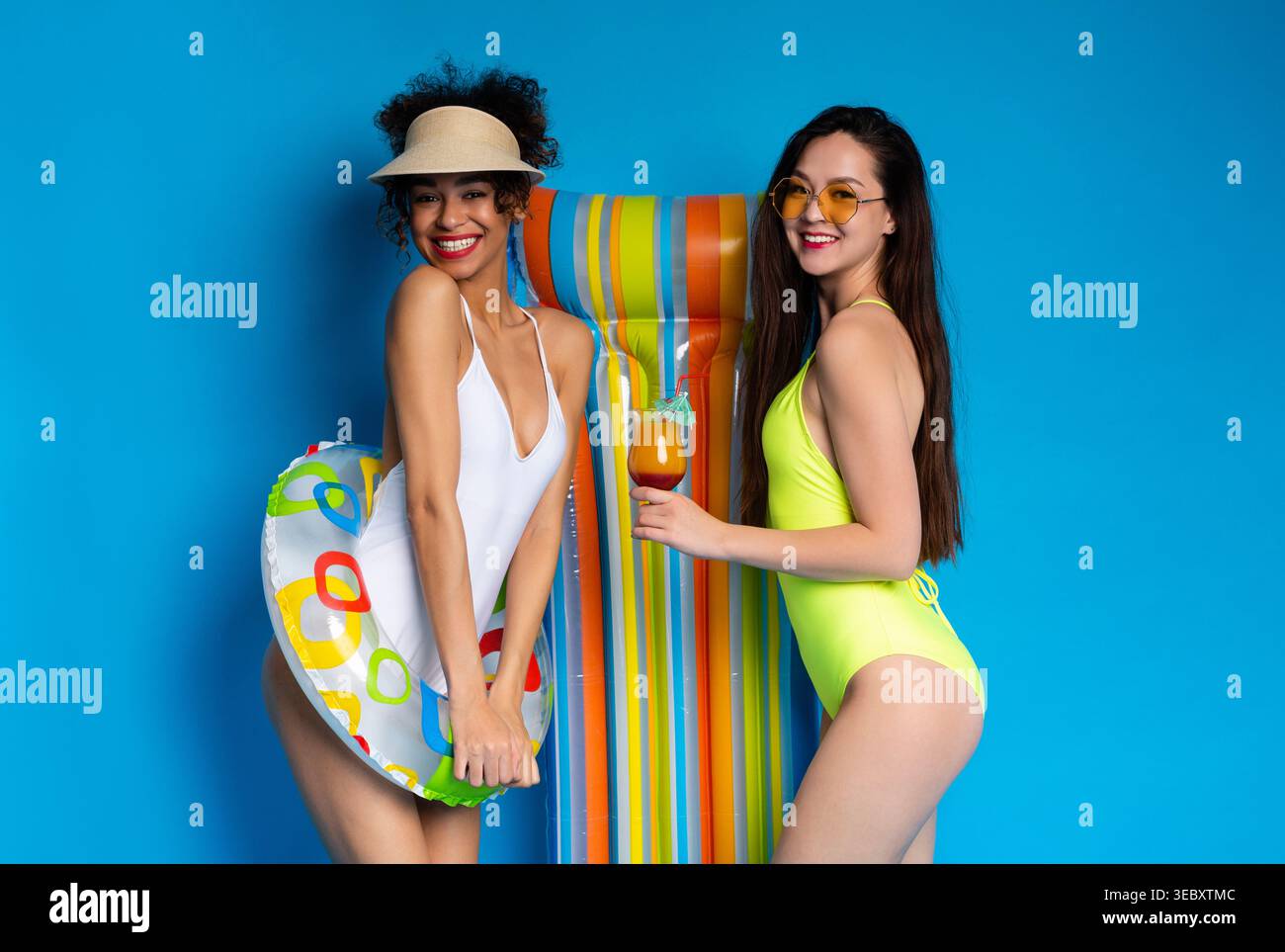 Two Friends Enjoying Summer at the Pool With Colorful Float and Refreshing Drinks Stock Photo