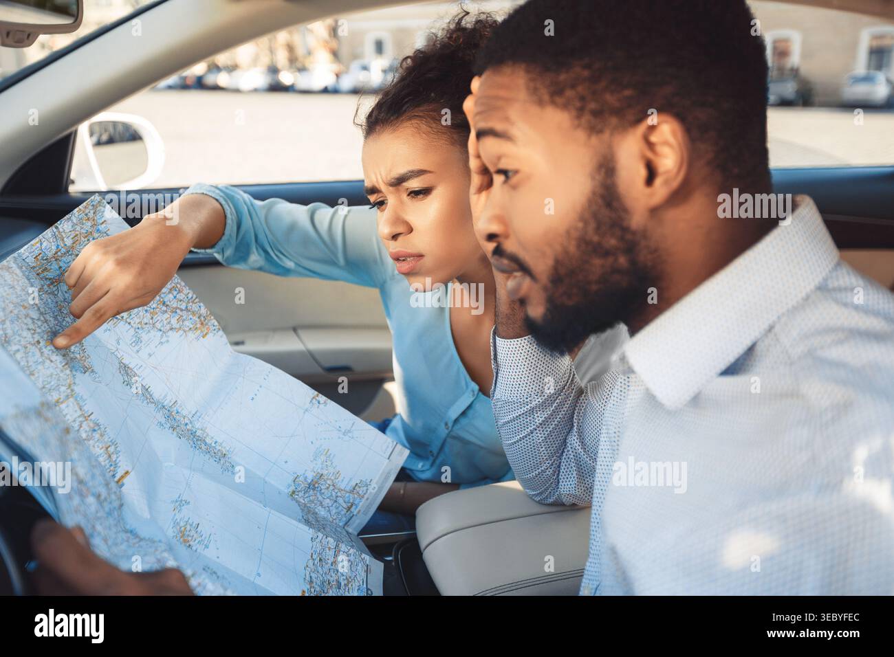 Young Couple Exploring a Map While Sitting in a Car During a Road Trip Stock Photo