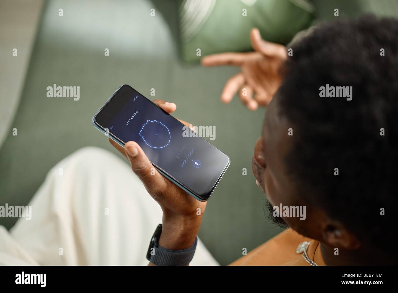 Black Man Using Smartphone Voice Assistant for Smart Home Control Stock Photo