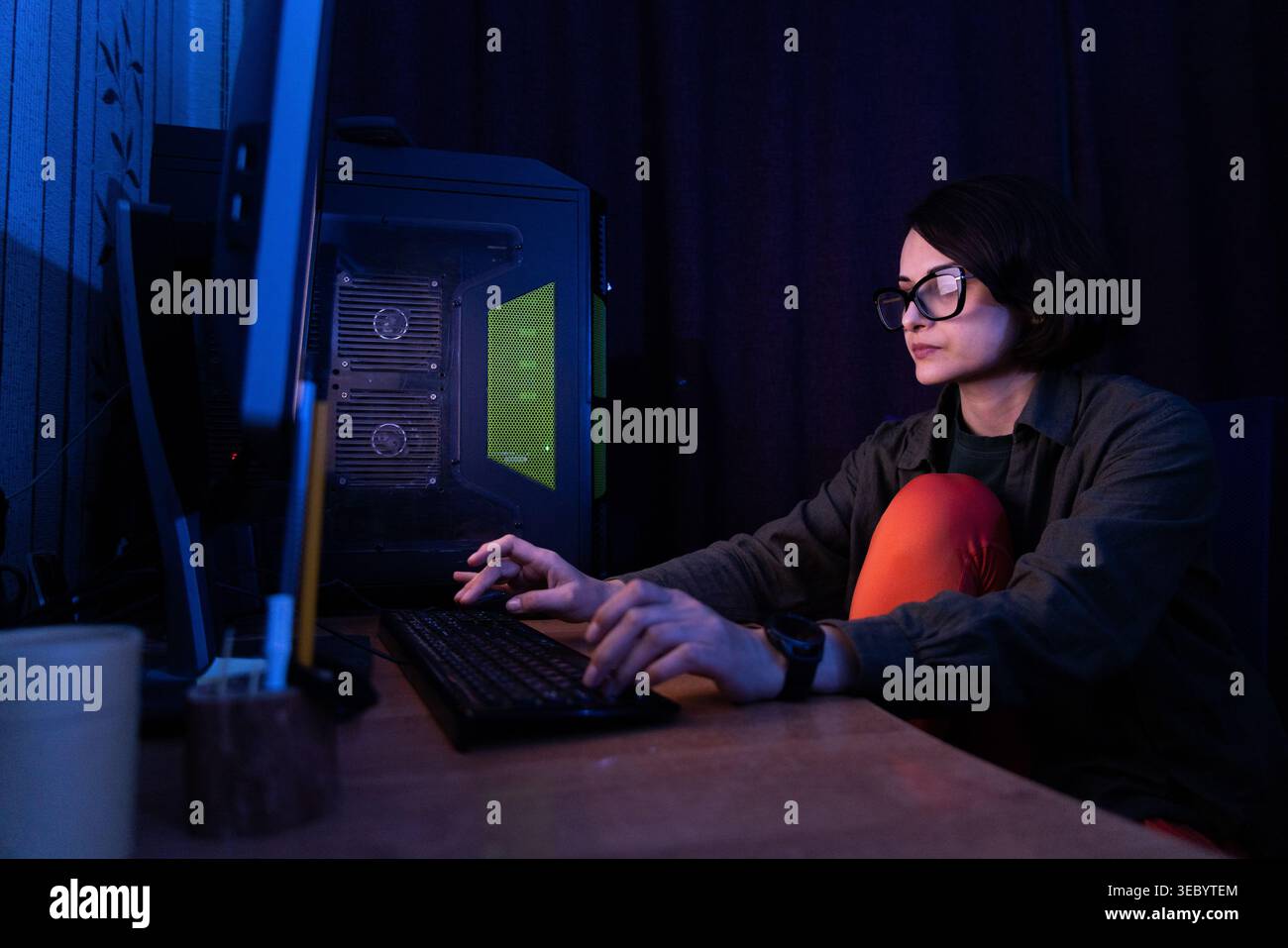 Woman Working on Desktop Computer in Low Light Stock Photo