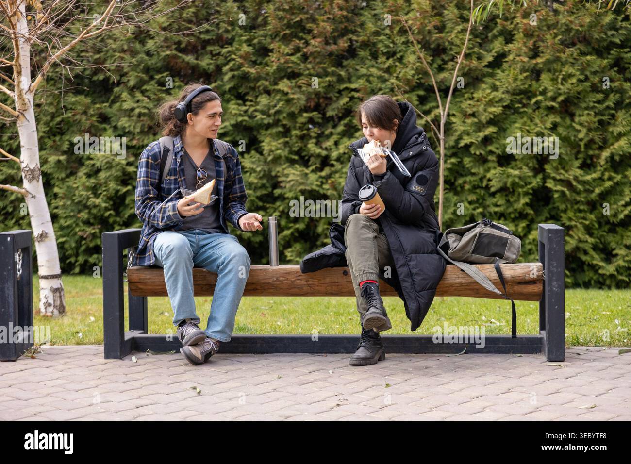 College students having lunch on park bench Stock Photo